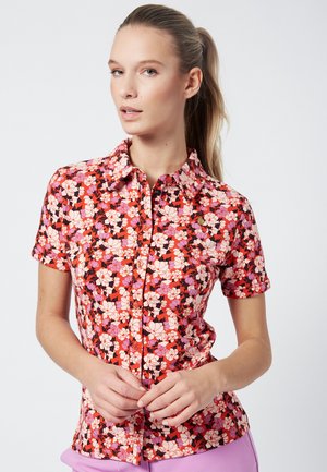 Camisa de manga corta en rojo con un patrón floral que presenta acentos en rosa, púrpura y negro. Diseño de botones con cuello. Textura suave.