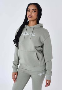 Lichtgroene hoodie met een voorzak en een capuchon met koord. Bevat witte geborduurde tekst. In combinatie met bijpassende strakke sweatpants.