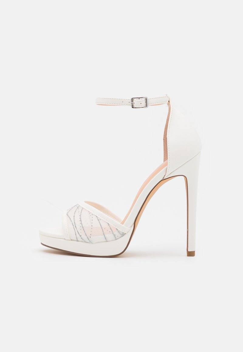 Sandale blanche à talons hauts avec une bride de cheville, panneau en maille transparente avec des coutures argentées et une semelle plateforme compensée pour une hauteur supplémentaire.