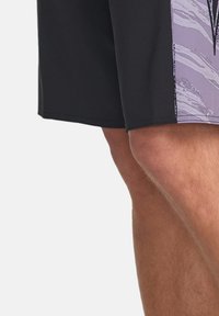 Pantaloni corti neri con un design astratto viola sul lato. Realizzati in materiale liscio e leggero, con una vestibilità strutturata e un orlo pulito.