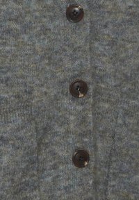 Grå strikket cardigan med tekstureret stof, store brune knapper og en subtil grønlig nuance. Nærbillede af knapdetaljer.