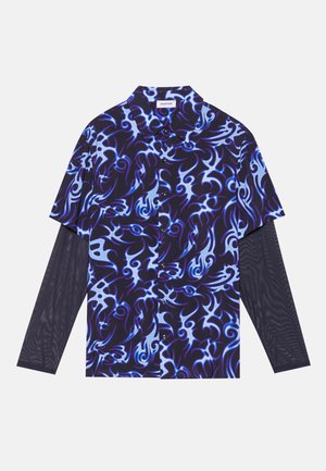 Kurzarmhemd mit einem blauen und lila Flammenmuster auf dunklem Hintergrund, darunter einem leichten Mesh-Langarmunterlayer.