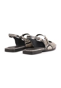 Sandalias de estampado de serpiente en blanco y negro con diseño de tirantes, que cuentan con punta redondeada y suela plana. Acento de hebilla en la correa.