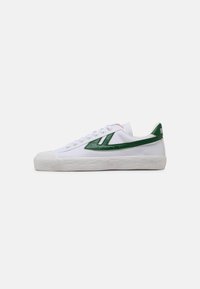 White canvas sneakers with green rubber accents, a textured white sole, and a low-top design featuring lace-up closure.