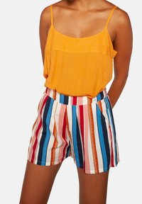 Orange sleeveless top paired with multicolored striped shorts featuring red, blue, and white vertical lines, with a textured fabric.