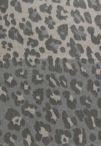 Tissu à motif léopard avec des taches irrégulières gris foncé et gris clair sur un fond atténué.