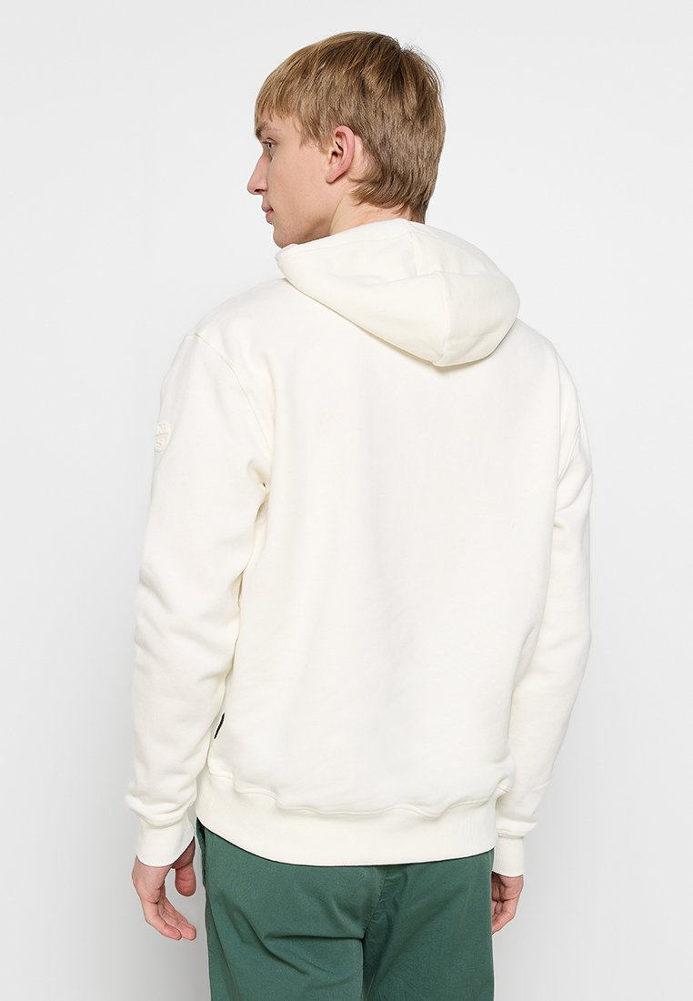 Sudadera crema con capucha ajustable, puños y dobladillo acanalados. Tejido suave, corte holgado, con un pequeño logo en el hombro izquierdo.