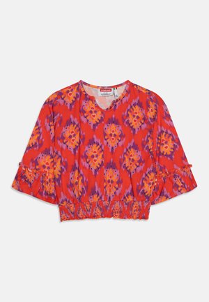 Raudona trumpa palaidinė su oranžiniais ir violetiniais gėlių raštais, apvali iškirptė ir voliotomis rankovėmis. Garsvo audinio juosmuo.