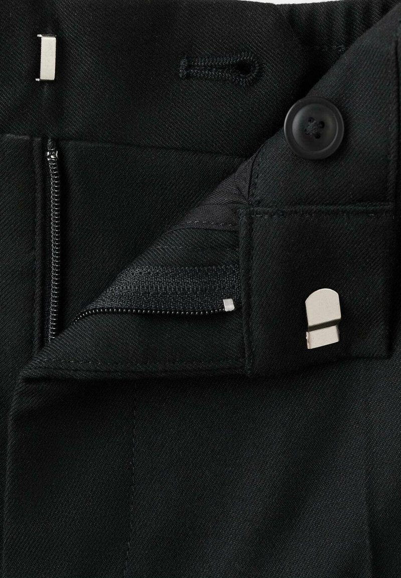 Pantaloni neri con chiusura a zip e bottone, dotati di un gancetto metallico e una tasca interna con zip, il tutto in un tessuto testurizzato.