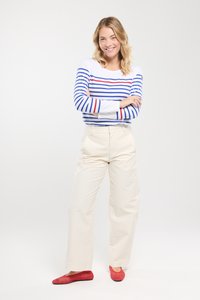 Gestreepte longsleeve shirt in het wit met blauwe en rode strepen, gecombineerd met crème wijde broekspijpen en rode textuur flats. Eenvoudig ontwerp, casual uitstraling.