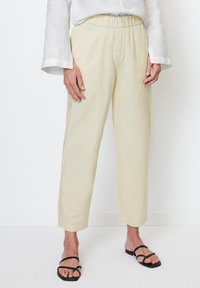 Ljust beige, byxorna med elastiskt midjeband har en lös passform och rak bendesign. Tillsammans med svarta sandaler ser tyget texturerat och andningsbart ut.
