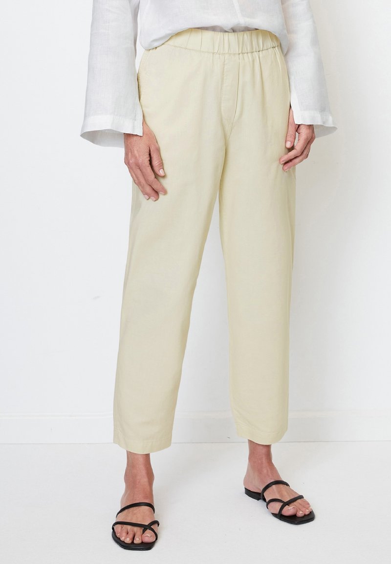 Ljust beige, byxorna med elastiskt midjeband har en lös passform och rak bendesign. Tillsammans med svarta sandaler ser tyget texturerat och andningsbart ut.