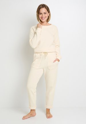 Crème-kleurige loungewear set met een geribde textuur, ronde hals en een elastische tailleband met verstelbaar trekkoord. Inclusief zijzakken.