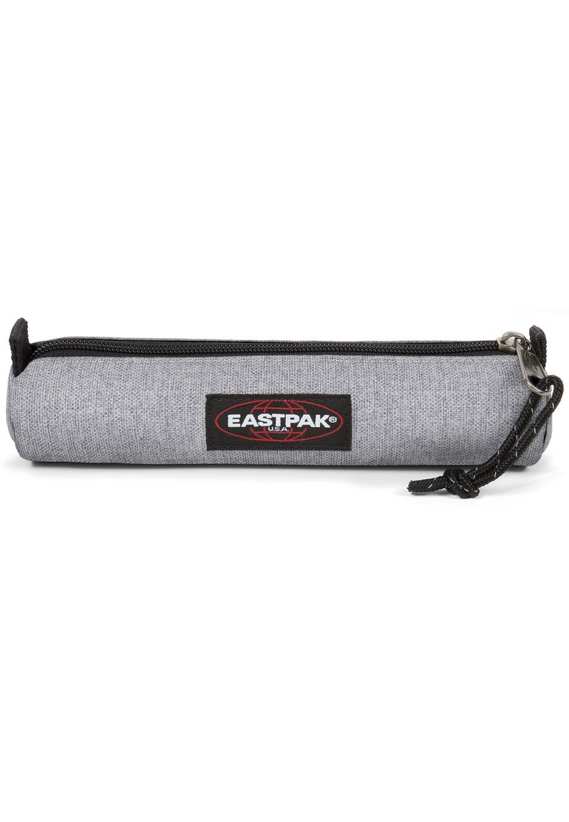 Estuche de lápices de tejido gris con una cremallera negra, que presenta un parche de marca en rojo y negro. Tiene forma cilíndrica y está hecho de un tejido texturizado.