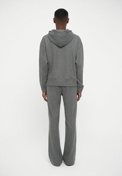 Felpa grigia con cappuccio e pantaloni abbinati realizzati in tessuto morbido. Il design include un cappuccio, polsini a costine e gambe dei pantaloni svasate senza motivi.