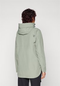 Giacca leggera verde chiaro resistente all'acqua con cappuccio, dotata di una ventola posteriore, maniche lunghe e un piccolo logo sul lato sinistro superiore.