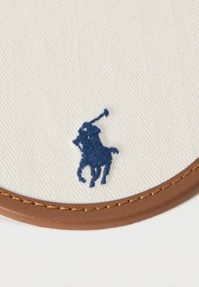 Μπλε κεντημένος παίκτης πόλο σε λευκό υφασμα με υφή και καφέ ραμμένο δερμάτινο περίγραμμα.