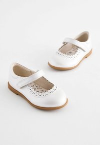 Weiße Leder-Mary-Jane-Schuhe mit einer gerüschten Öffnung, Klettverschluss und floralem Futter. Sandfarbene Gummisohle.