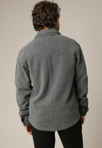 Grijze flanellen shirt met een kraag, knoopmanchetten en een licht gebogen zoom. De stof heeft een gestructureerde afwerking en een gemiddeld gewicht.