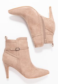 Bottines en suède beige à bout pointu, avec fermeture éclair, accents perforés et un talon aiguille de 8,5 cm.