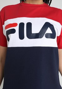 Tričko s blokováním barev v červené, bílé a námořnické modré barvě, se silným černým logem FILA uprostřed. Vyrobeno z bavlny s designem kulatého výstřihu.
