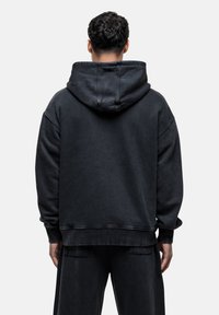 Felpa nera con cappuccio dal taglio rilassato, con dettagli cuciti, polsini a coste e orlo dritto. Realizzata in tessuto morbido.