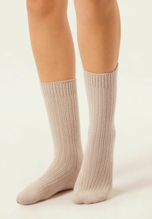Chaussettes côtelées beige clair en matériau doux, d'une longueur mi-mollet et avec une finition texturée.