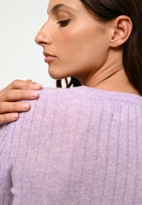 Pull en maille côtelée de couleur violet clair, avec un col rond. Texture douce, silhouette ajustée et détails de couture d'épaule marqués.