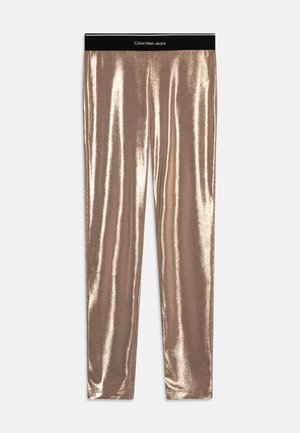 Metallic guld leggins med en blank overflade og en sort Calvin Klein Jeans talje. Tætsiddende pasform, hel-længde design.