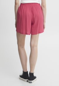 Leichte, rosa, knielange Shorts mit einem elastischen Bund. Einfaches Design mit einem strukturierten Stoff und einem lockeren Sitz.