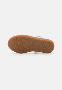 Suela de un zapato con un material de goma de color marrón claro, texturizada con patrones florales y en espiral, que proporciona agarre y estabilidad.
