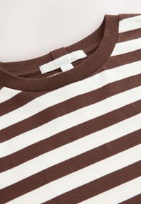 Barna-fehér csíkos, puha pamutból készült póló, kerek nyakkivágással és hátul "N.82" feliratú címkével.