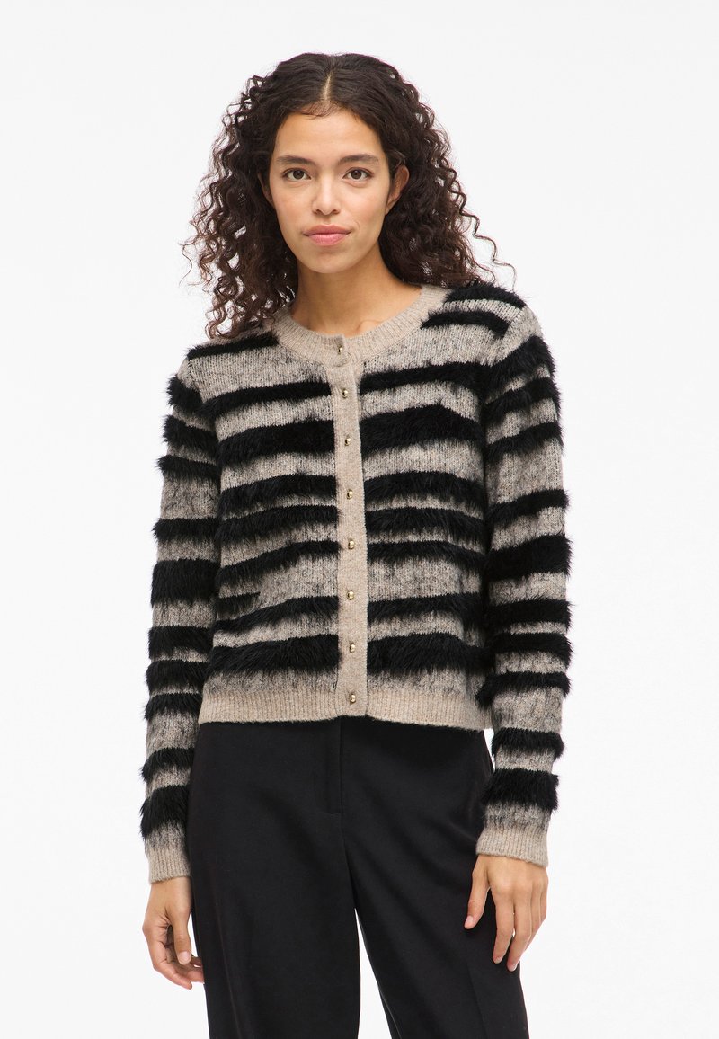 Cardigã às riscas em bege suave e preto, com uma textura espessa de pelo sintético, fecho com botão e punhos canelados.