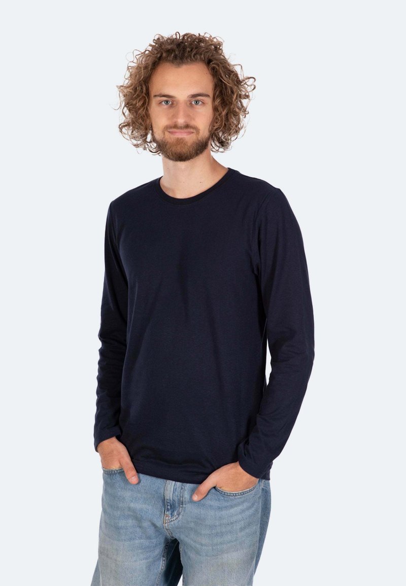 Marineblaues Langarm-T-Shirt aus weichem Material mit Rundhalsausschnitt und figurnaher Silhouette, kombiniert mit hellblauen Jeans.