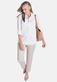 Weißes Button-up-Hemd, hellgraue gemusterte Hose, beige Absätze und eine beigefarbene Tragetasche. Glatter Stoff und lockere Passform.