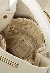 Borsa beige con esterno in pelle sintetica, accessori in oro e interno simile alla seta. Presenta una tasca con zip e un etichetta con il logo.