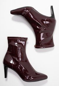 Bottines en cuir verni bordeaux à bout pointu, fermeture éclair latérale et talons aiguilles de 4 pouces. Texture lisse et brillante avec des détails de couture.