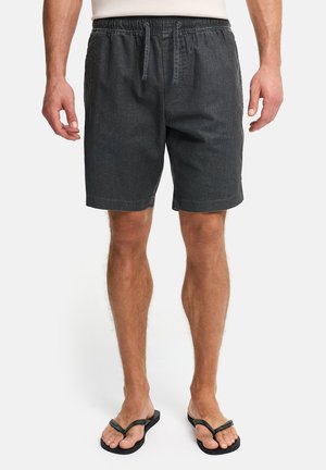 Shorts décontractés pour hommes en gris foncé, avec taille élastique et cordon de serrage, portés avec des tongs noires, montrés de la taille aux pieds.