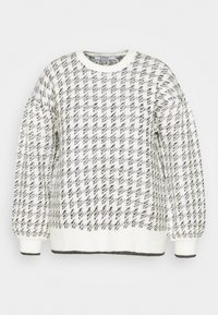 Pull blanc avec un motif pied-de-poule noir, encolure ras du cou, manches longues bouffantes, et bords côtelés.