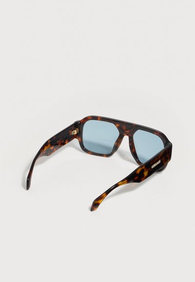 Γυαλιά ηλίου με σκελετό από χελώνα, τετράγωνα φακούς με μπλε απόχρωση και ψαλίδια φαρδιά, με το λογότυπο Versace στο δεξί ψαλίδι.