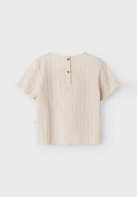 Top a maniche corte, di un delicato rosa chiaro, con texture a righe verticali, orlo scallop e chiusura a chiave sul retro con due bottoni.