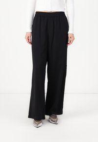 Black wide-leg pants made of soft fabric with an elastic waistband. Features a smooth texture and loose fit for comfort.