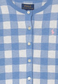 Cardigan à carreaux bleu clair et blanc en matière tricotée douce. Présente un col rond, une fermeture à boutons, et un petit logo rose sur le côté gauche.