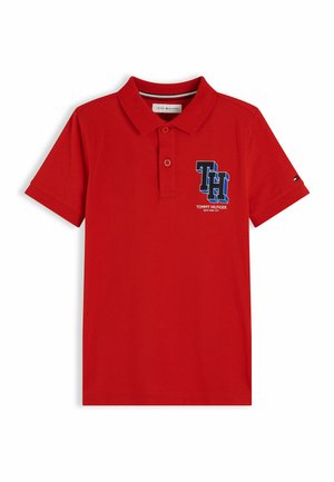 Czerwona koszulka polo z krótkim rękawem, kołnierzykiem, dwoma guzikami oraz granatowym logo "TH" z tekstem "Tommy Hilfiger New York City" na piersi.