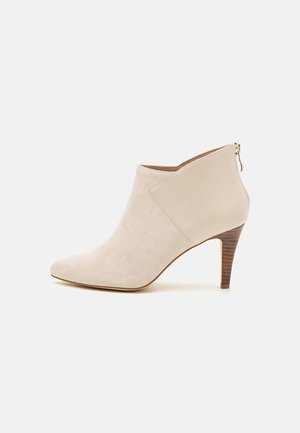 Beige dame ankelstøvle med spids tå, ruskindsfront, glat læderbag, lynlås i siden og mellemhøj stabbet hæl.