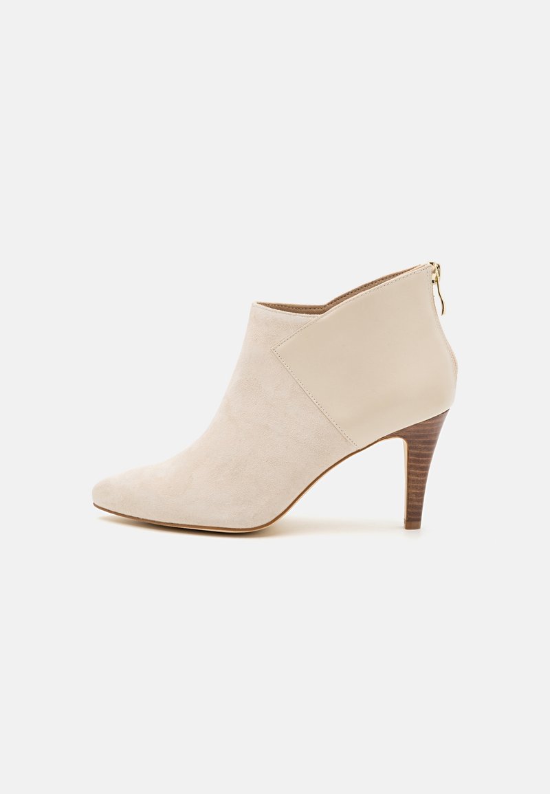 Bottine beige pour femme à bout pointu, avant en suède, arrière en cuir lisse, fermeture zippée latérale, et talon empilé de hauteur moyenne.