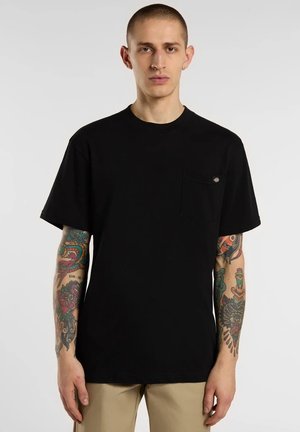 T-shirt nera in cotone con maniche corte, scollo rotondo e taschino sul petto a sinistra. Presenta un piccolo logo sulla tasca e una vestibilità comoda.