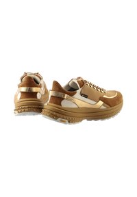 Baskets en daim marron avec accents dorés et finition blanche, lacets ronds, et semelle texturée. Caractéristiques d'un design rembourré et marquage Vibram.