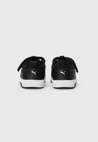 Des baskets Puma noires avec des semelles blanches présentées de l'arrière sur un fond léger gris uni.