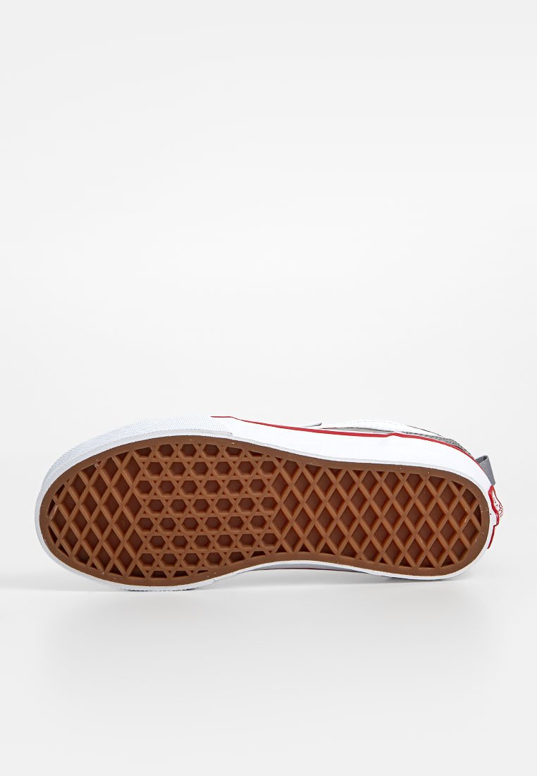Zapatillas Vans con parte superior de lona blanca, acentos rojos y una suela de goma marrón con un patrón de diamante para un mejor agarre y textura.